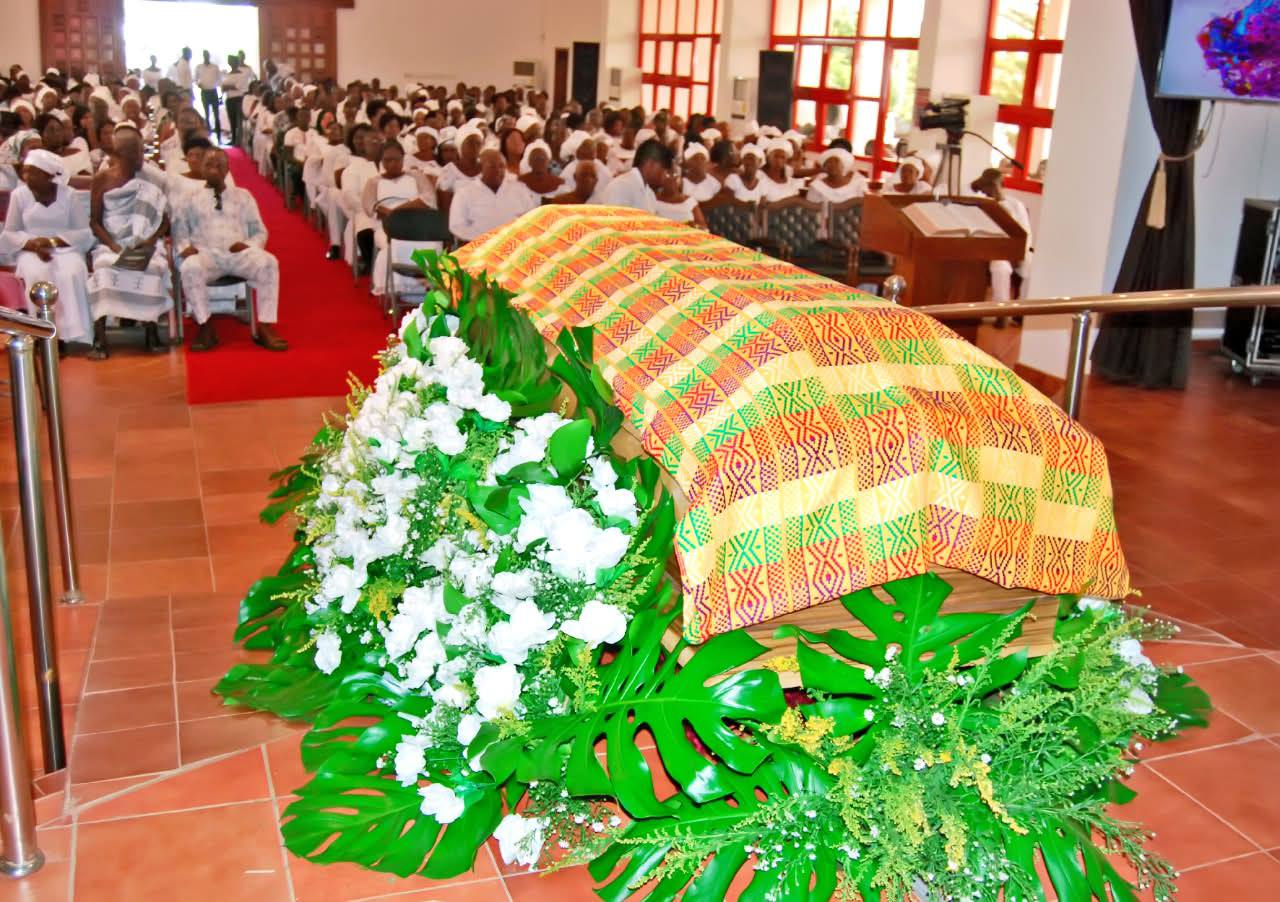 Handwoven Kente drape and ceremonial floral tribute on memorial casket