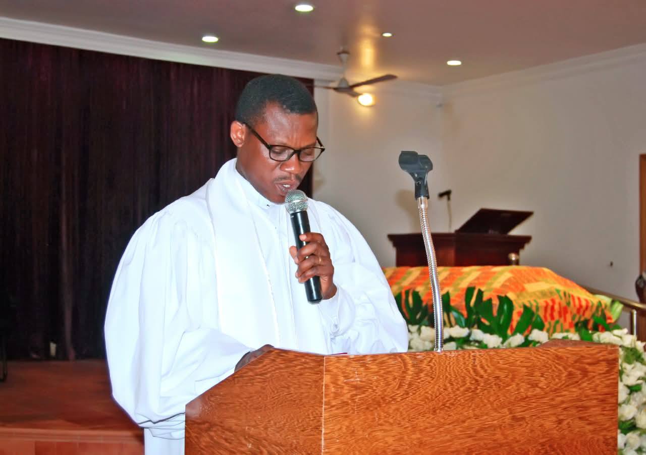 The officiating clergy delivering the sermon, prayer of thanksgiving, and scripture readings from the timber sanctuary lectern.