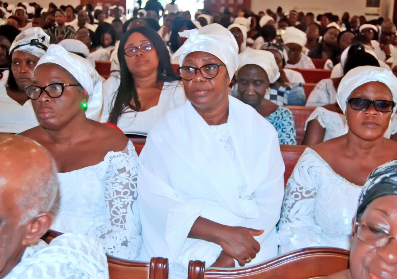 Family matriarchs and chief mourners dressed in white lace attire and headwraps, holding solemn vigil during the farewell tributes.